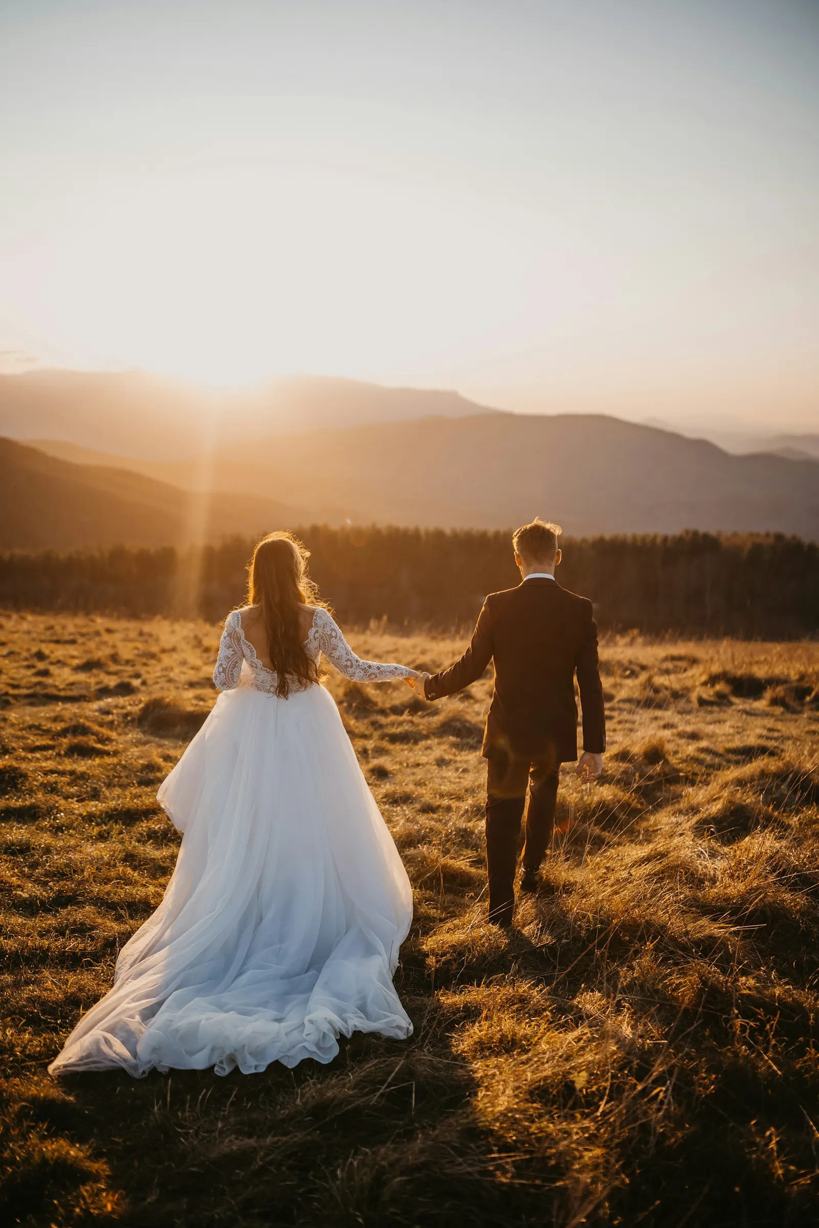 Jeunes mariés main dans la main au coucher du soleil